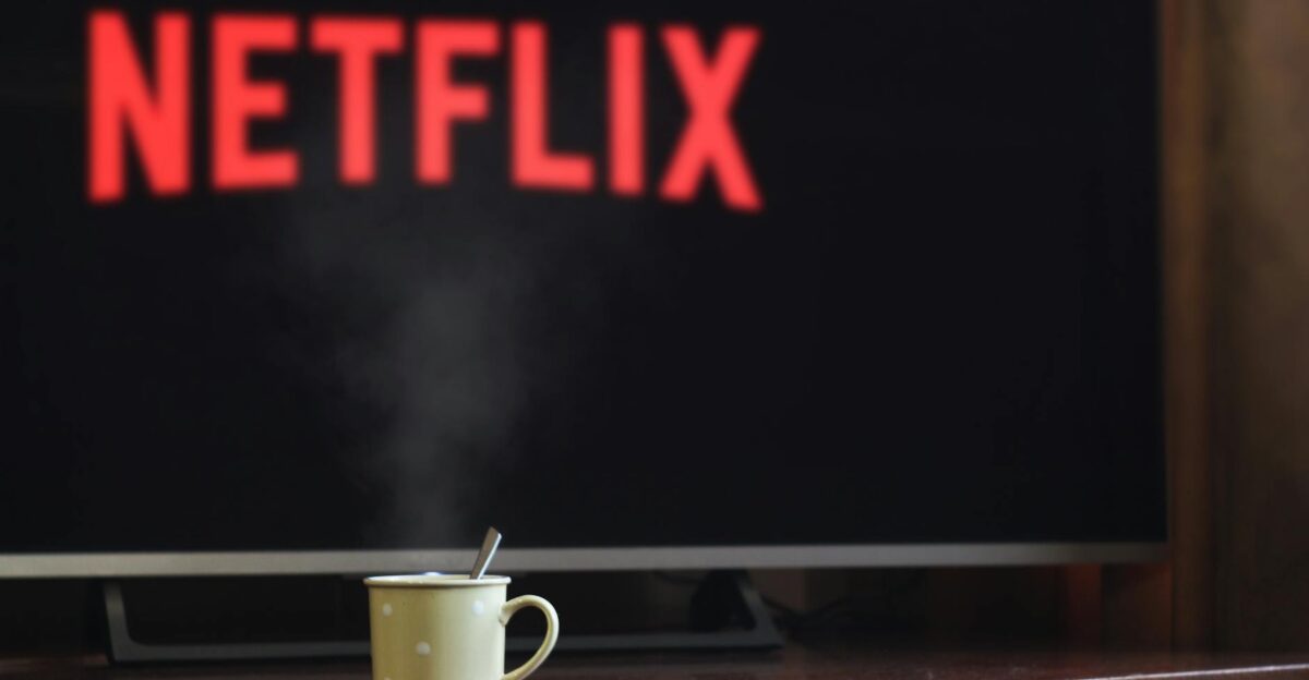 A steaming mug on a table in front of a TV displaying Netflix creating a cozy indoor atmosphere