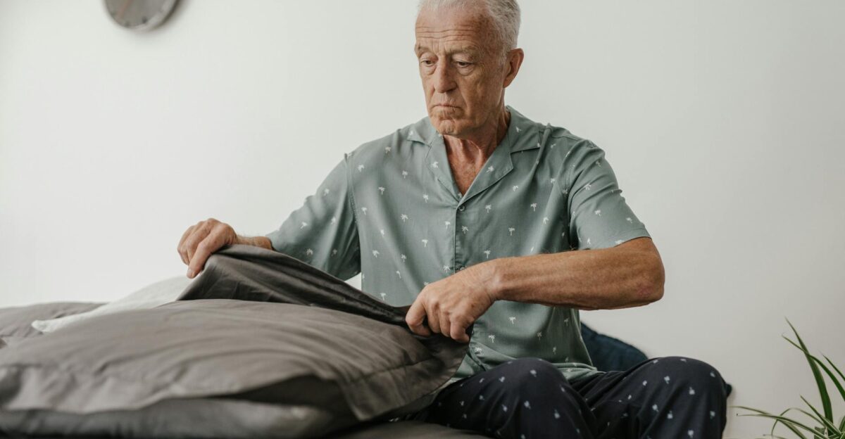 Elderly man carefully making bed showcasing daily lifestyle routine indoors