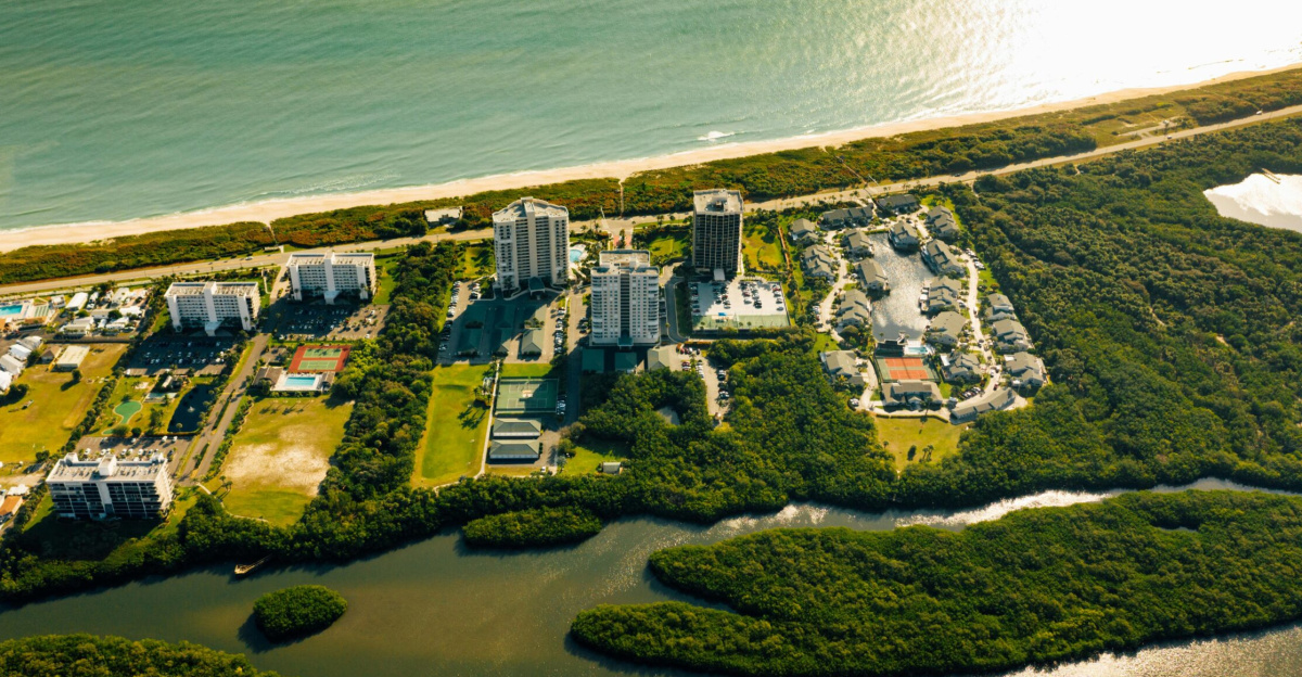 Stunning aerial view showcasing a coastal city with modern buildings and lush greenery by the ocean.