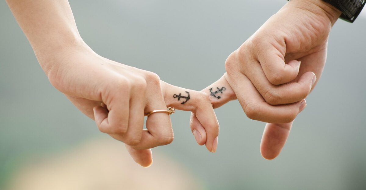 valentines day background couple hands tattoos fingers intertwined anchor tattoos lovers together touch relationship closeup