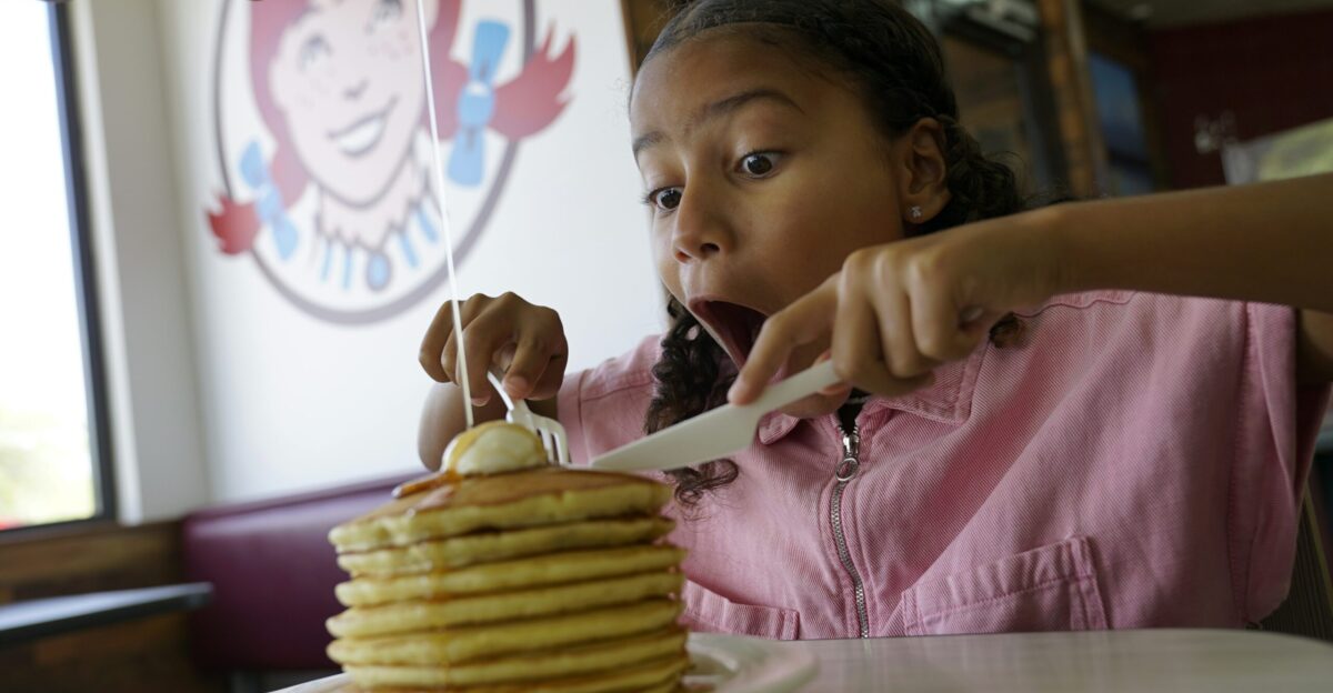 Young girl eating a large stack of pancakes