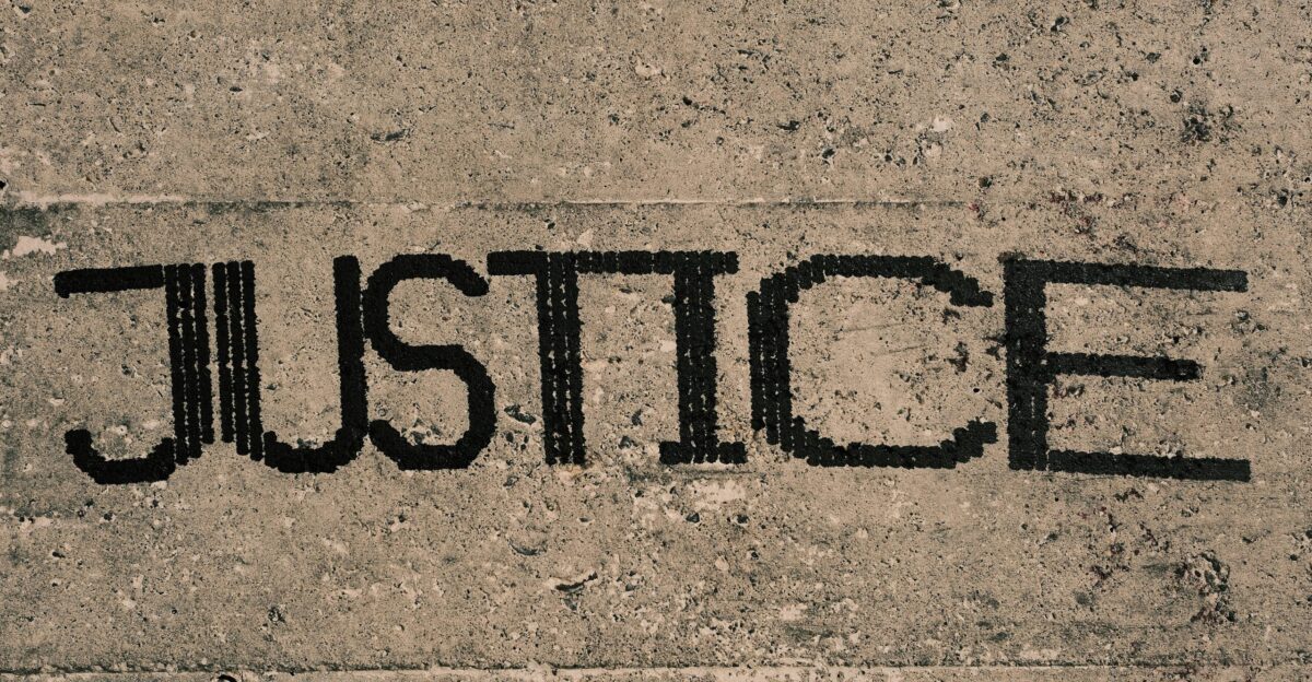 the word justice written in black ink on a concrete surface