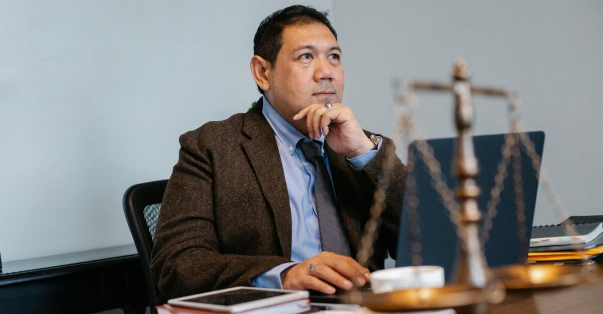 Asian lawyer at work with laptop and legal scales focused and thoughtful