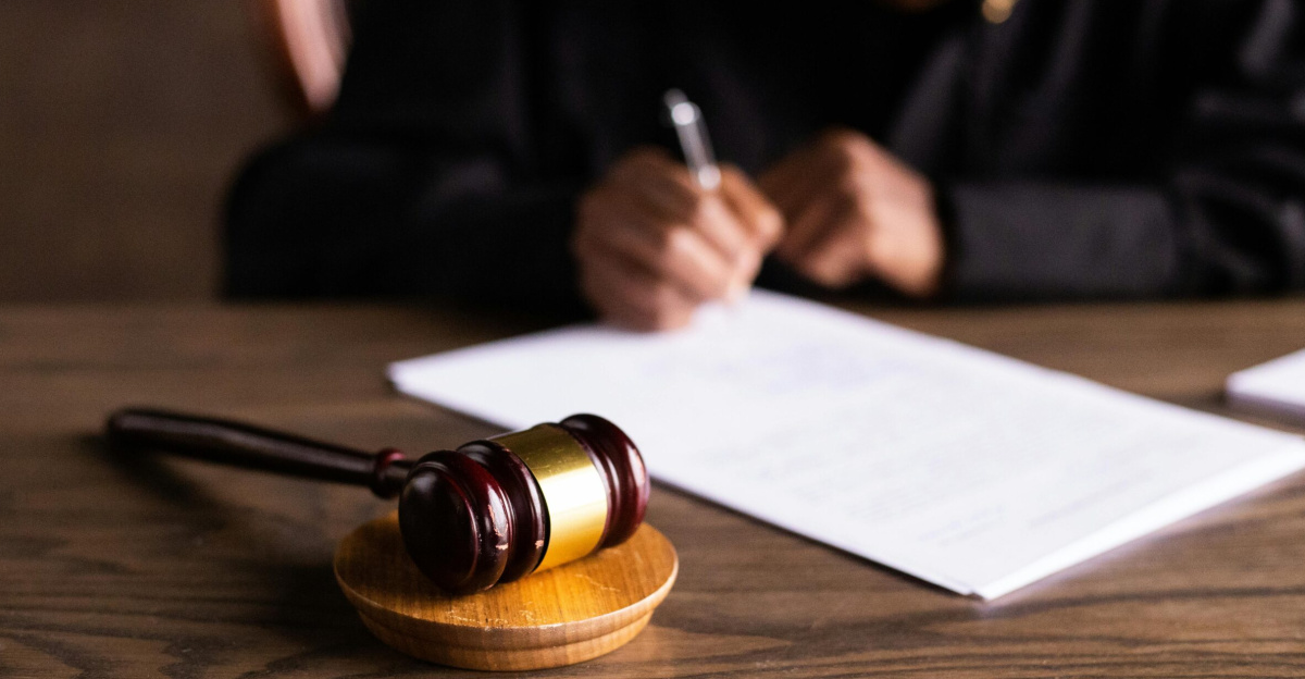 Judge signing documents at desk with focus on gavel, representing law and justice.