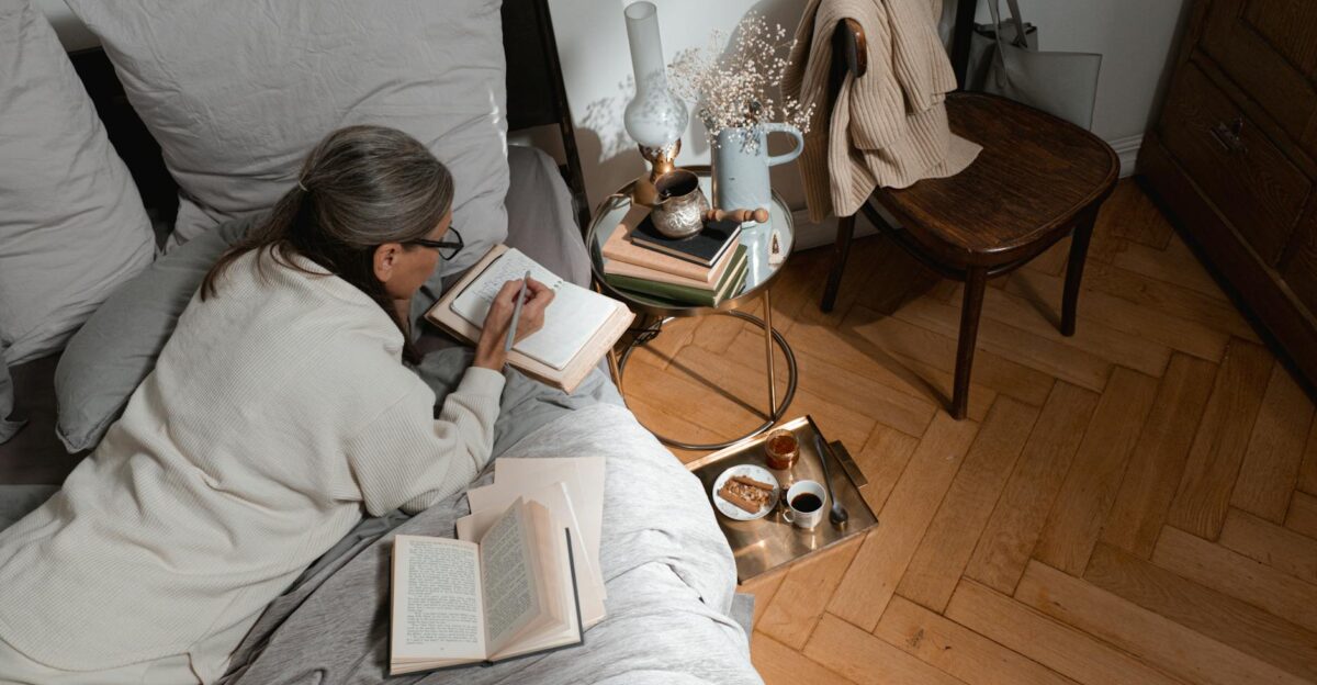 Senior woman takes notes in bed with coffee books and cozy decor on a peaceful morning