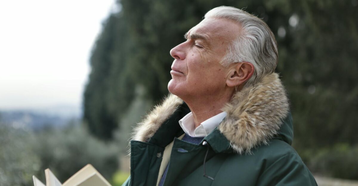 Senior man with white hair eyes closed enjoying fresh air in Tuscany s natural setting
