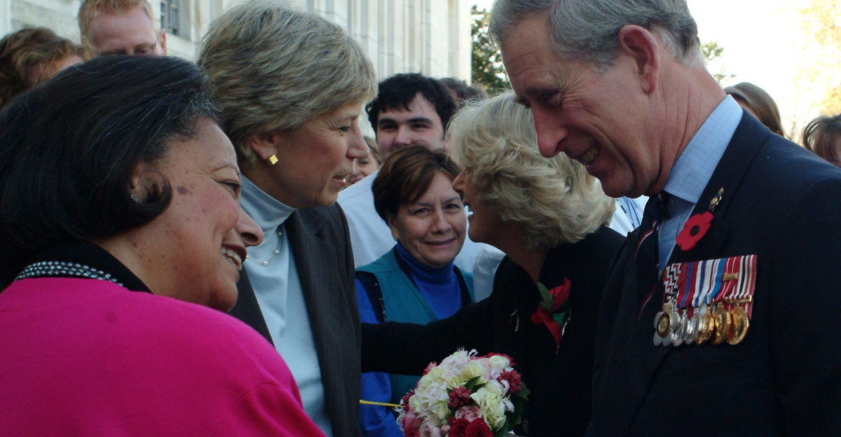Group of figures outdoors; in the foreground, Karen Hastie Williams and Charles, Prince of Wales, shake hands.