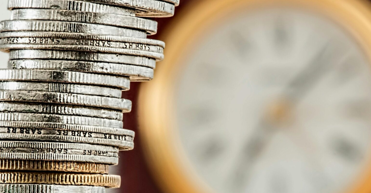 A close-up image of stacked coins with a blurred clock, symbolizing time and money relationship.