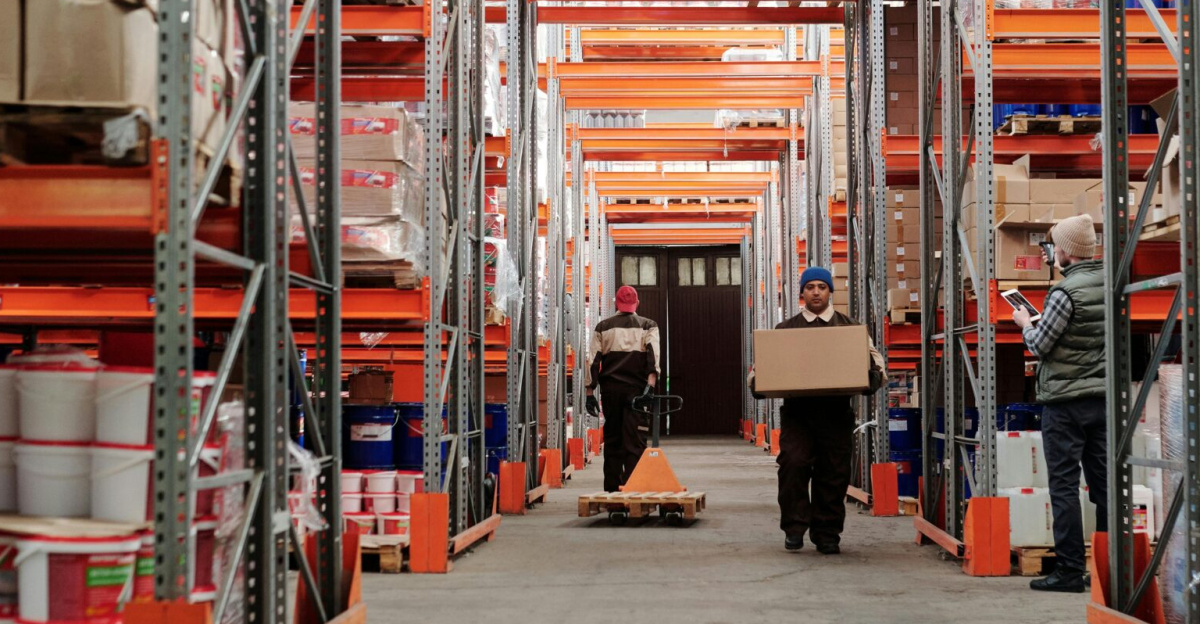 Warehouse interior showing workers handling boxes and organized shelves filled with products.