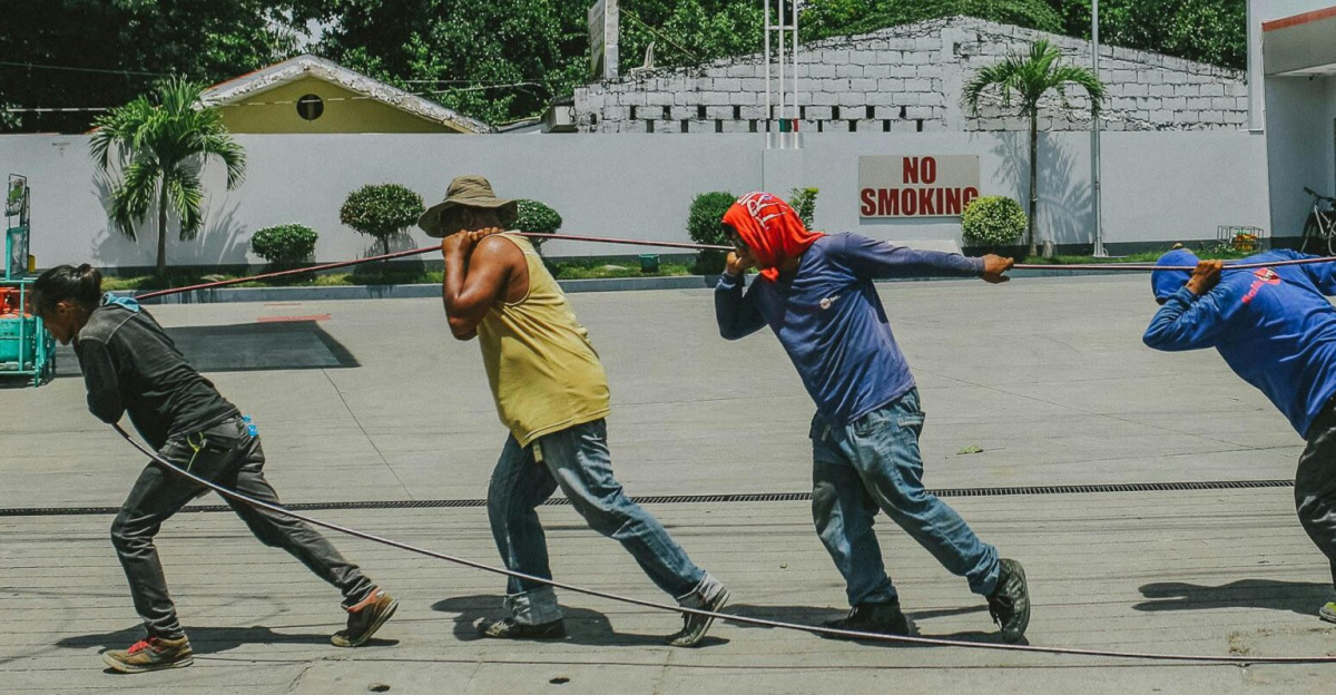 A group of workers installing cables at a gas station during daytime.