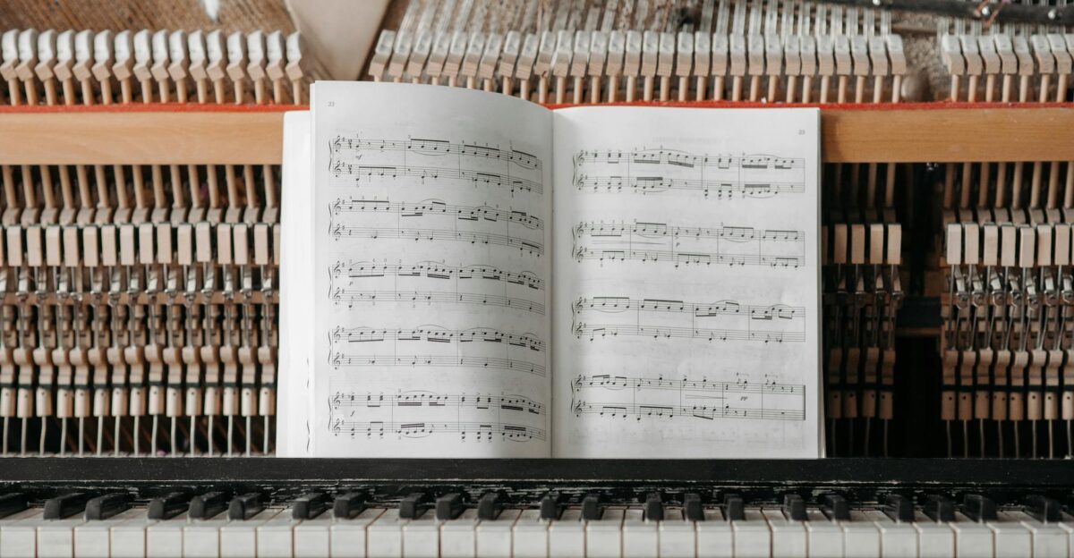Detailed view of piano internals with sheet music placed on keys showcasing the intricate mechanics