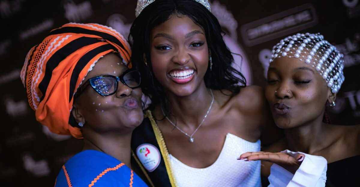 A beauty queen smiles with two women