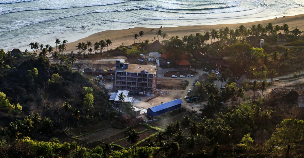A scenic aerial view of construction near a tropical beach during sunrise.