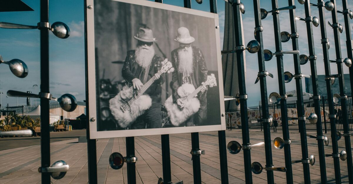 A black and white photo of a man playing guitar behind a fence